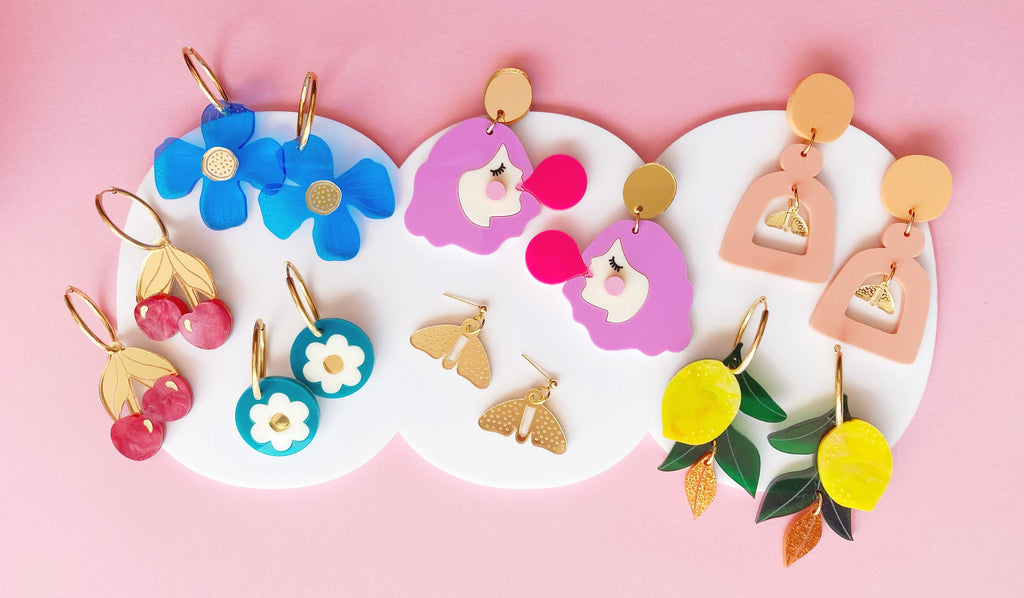 Colorful earrings displayed on a pink background